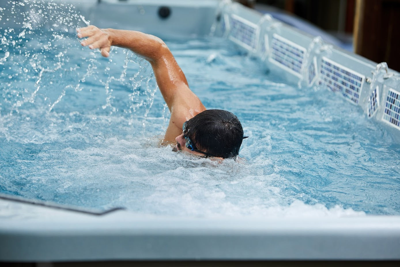 A man swimming in a swim spa with a water splash