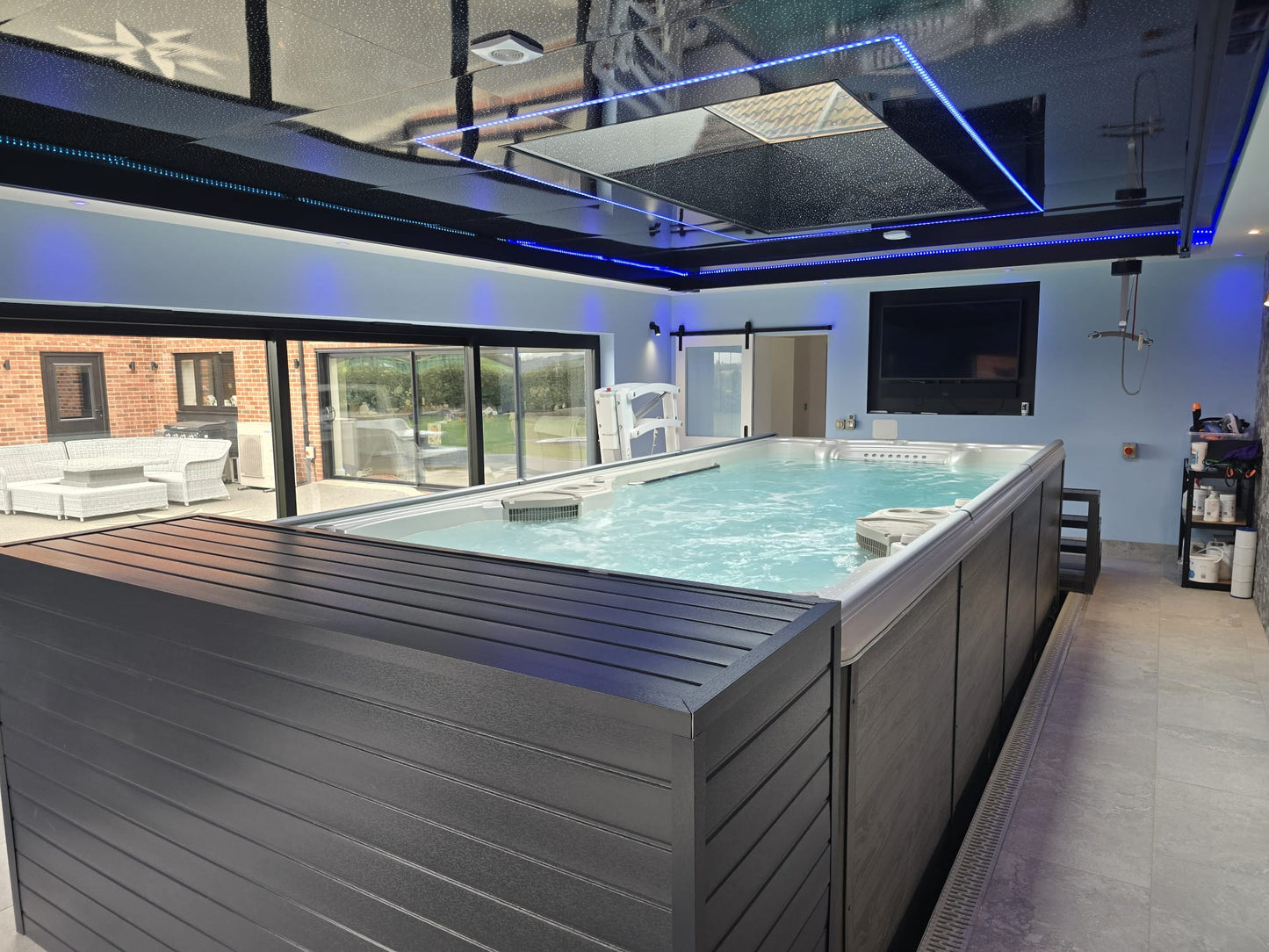 Swim Spa installed indoors with an EZ Glide automated cover fitted to it.