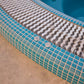 close up image of a mosaic hot tub with overflow grate