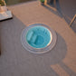Round mosaic hot tub with blue water on a tiled patio